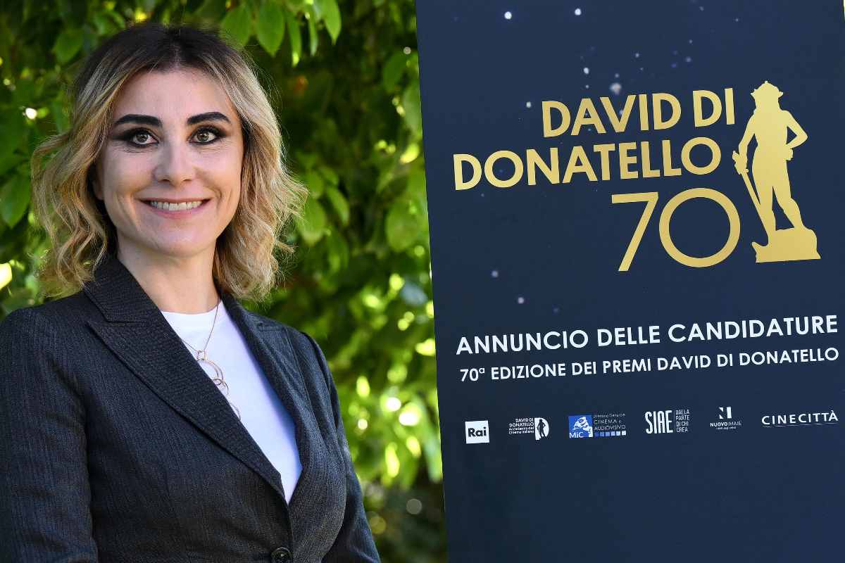 donna sorride davanti il cartellone dei david